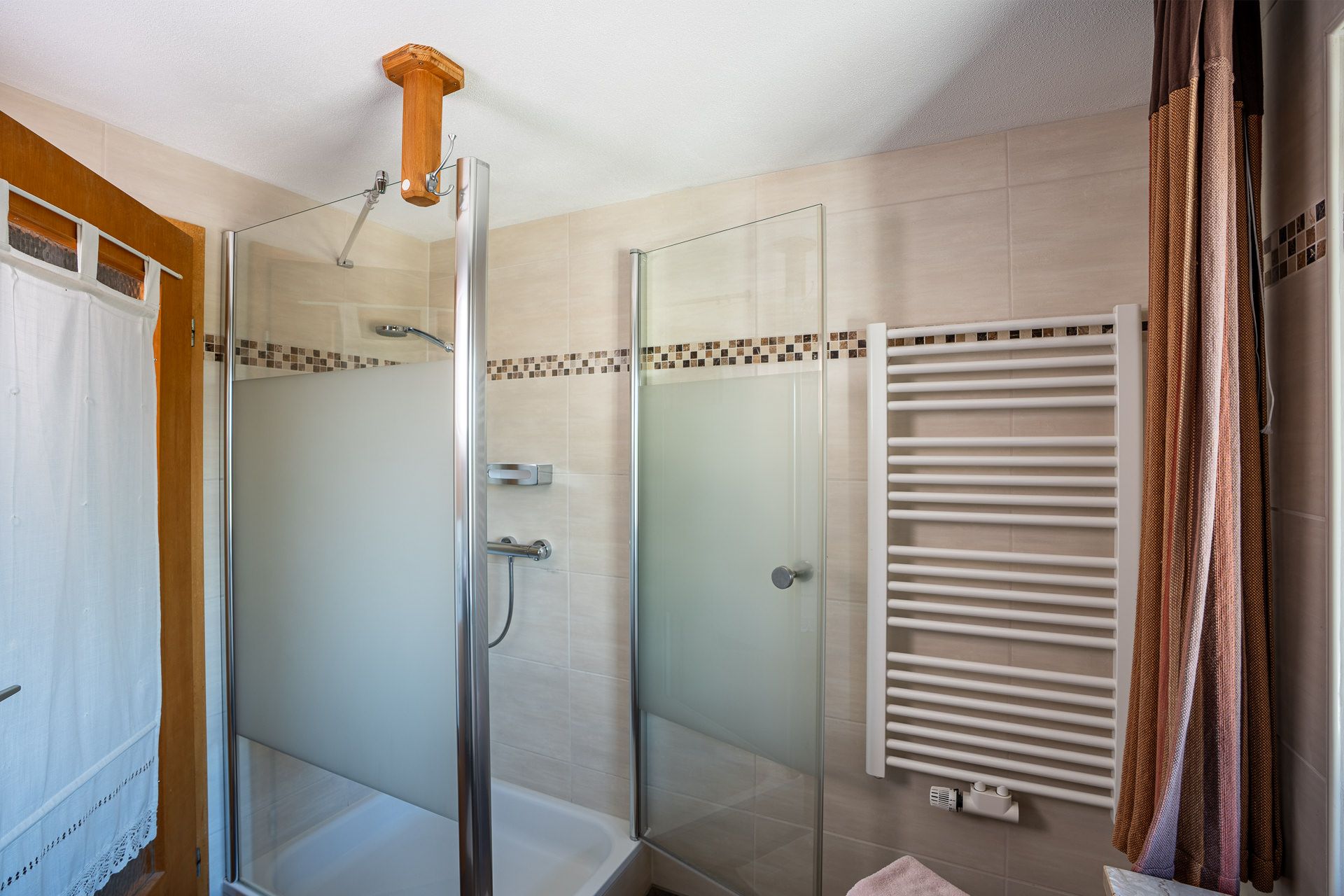 Shower cubicle with glass doors and a heated towel rail