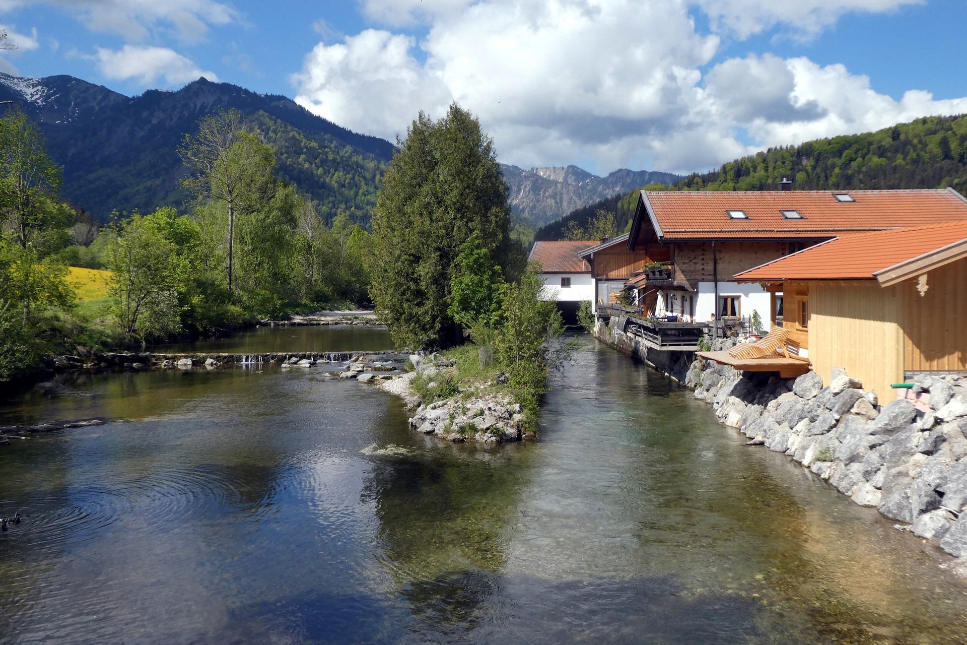 Klare Leitzach mit Kiesinsel an der Sägemühle in Mühlau, dahinter Berge und Wolken