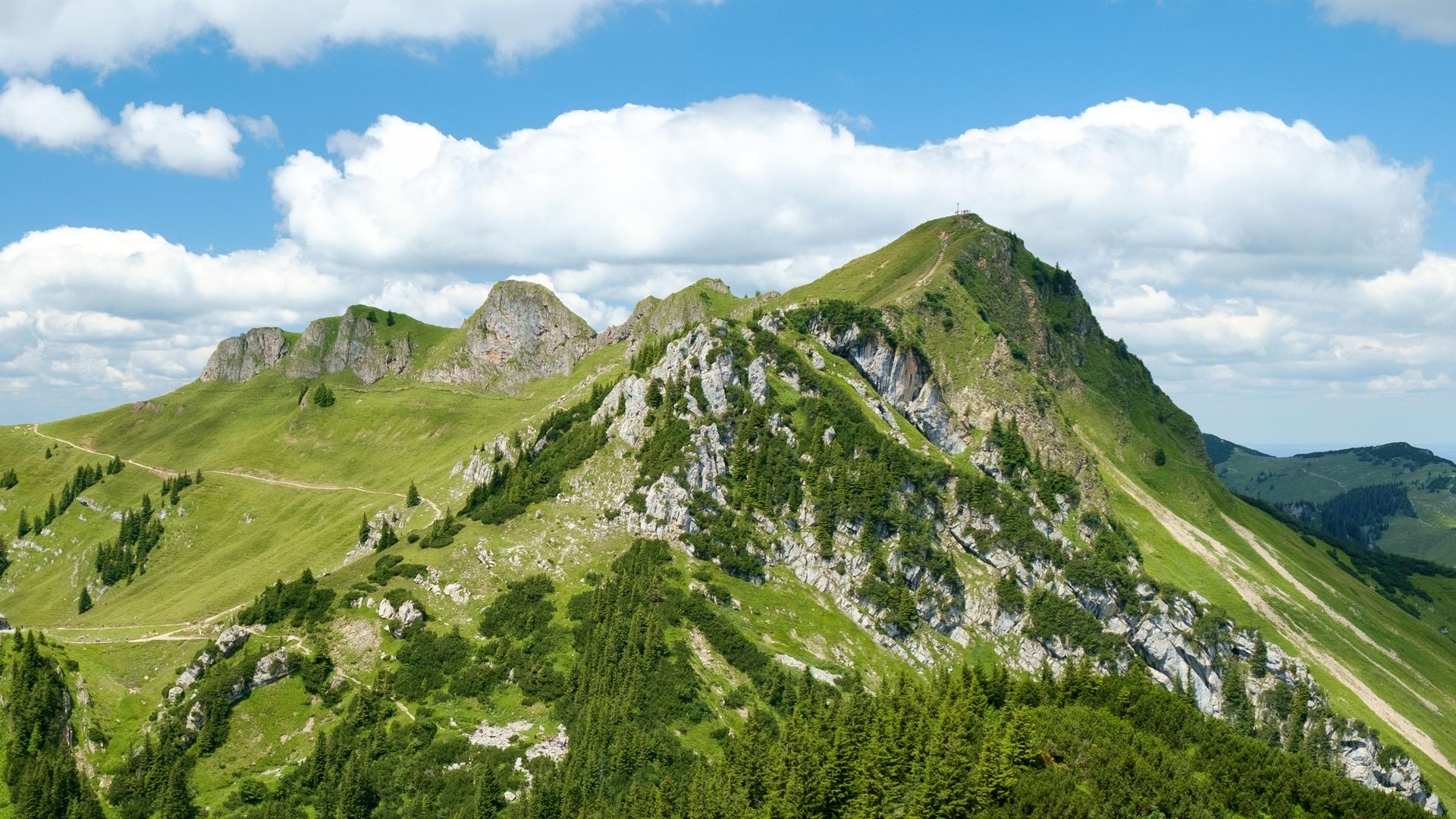 Grüner Grat zur Rotwand mit Gipfelkreuz unter Quellwolken