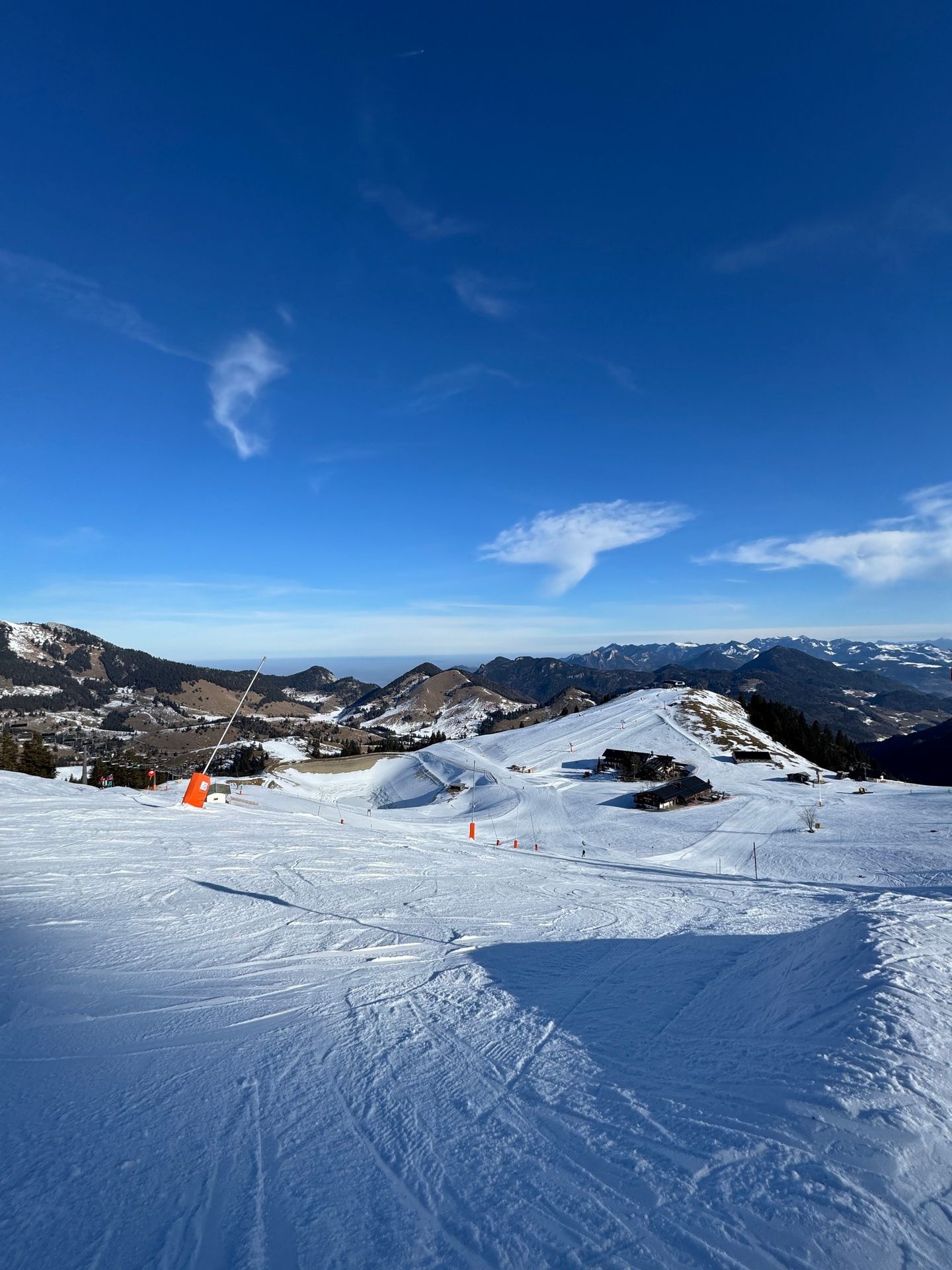 Präparierte Skipiste am Sudelfeld mit Pistenmarkierung, Blick über verschneite Berge unter tiefblauem Himmel